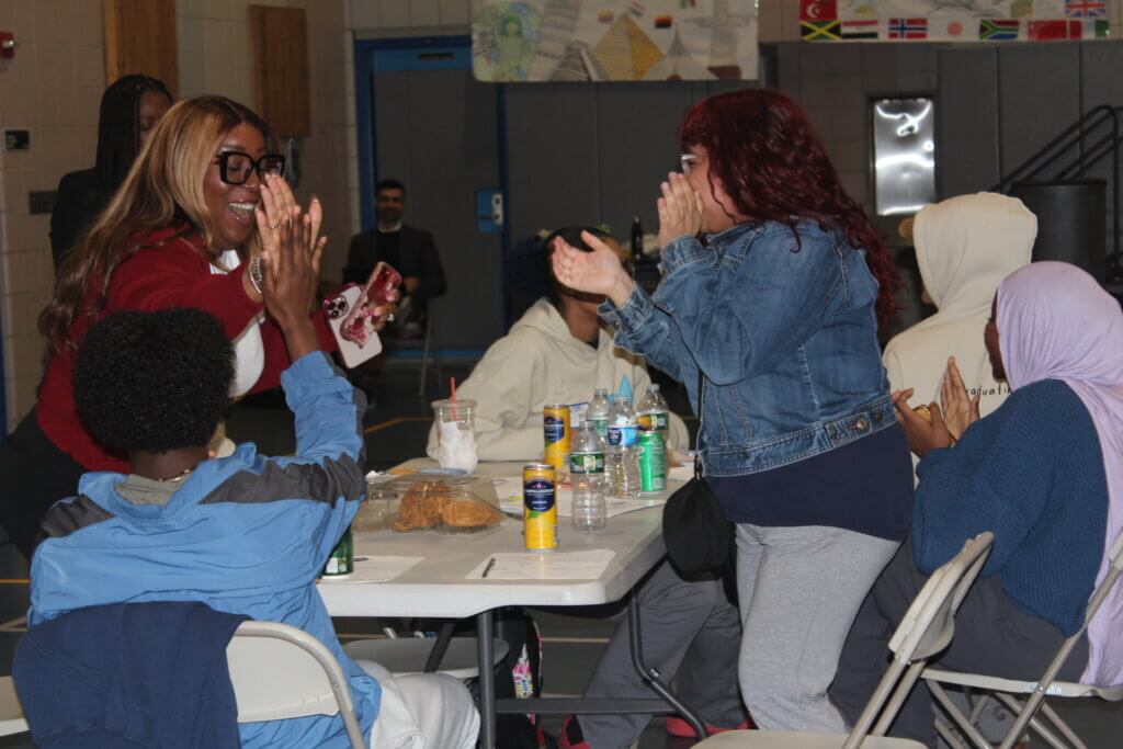 An Estée Lauder Companies volunteer and a student give each other a high five