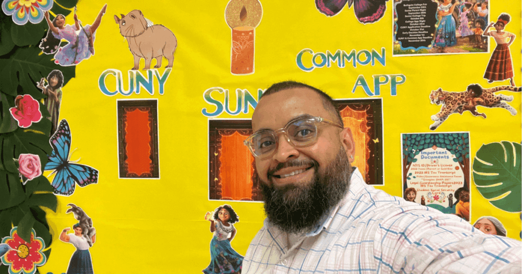 Benjamin smiles in front of a colorful bulletin board showcasing “CUNY,” “SUNY,” and “Common App” with cartoon characters and decorative elements.
