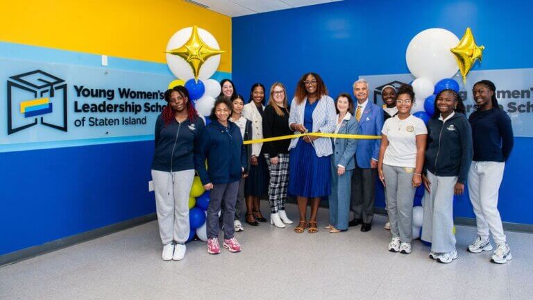 A group of people poses at a ribbon-cutting ceremony inside TYWLS Staten Island
