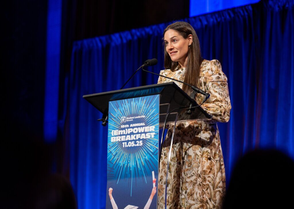 Lauren Coape-Arnold speaks at a podium during the (Em)Power Breakfast event