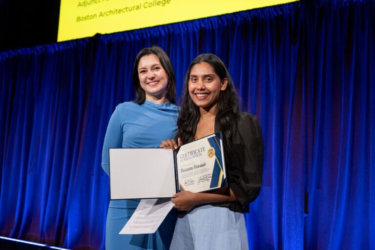 Julia Gamolina and Farzana Hossain stand on stage; one holds a certificate