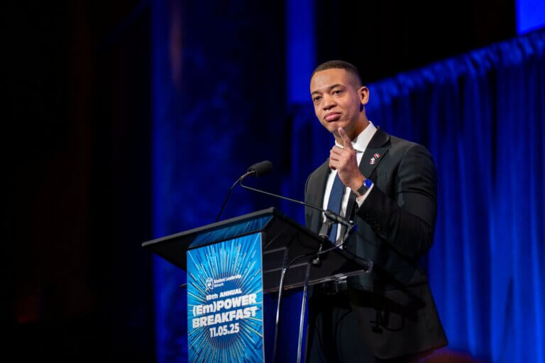 Ian Genao, in a suit, speaks at a podium