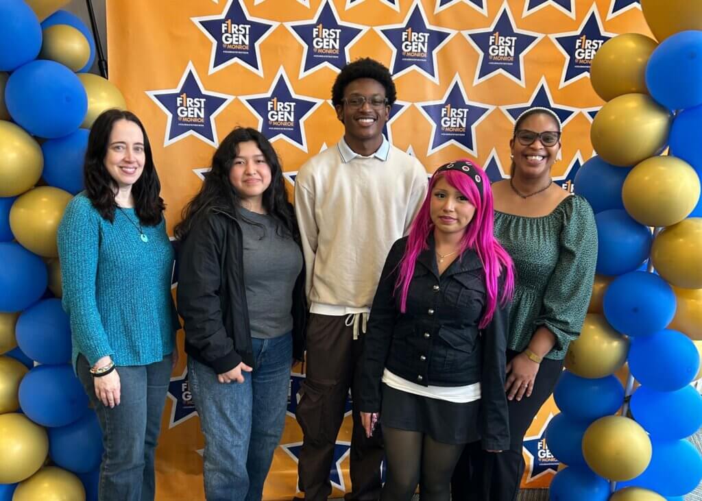 Five people stand in front of a First Gen step-and-repeat backdrop with blue and gold balloons on either side.