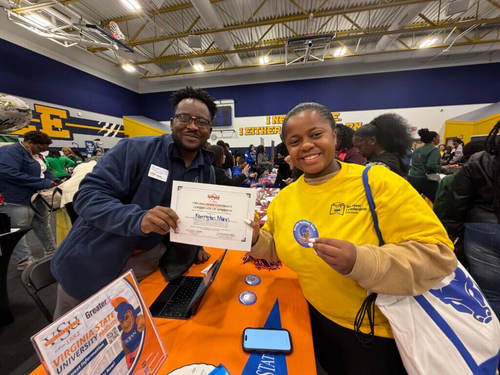 High school student and college admissions rep holding instant admissions certificate at HBCU college fair as part of the college application process