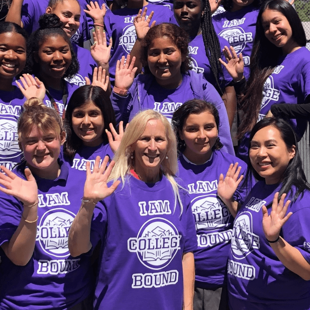 A group of people wearing matching purple I AM COLLEGE BOUND T-shirts showcase their leadership as they smile and wave at the camera outdoors.