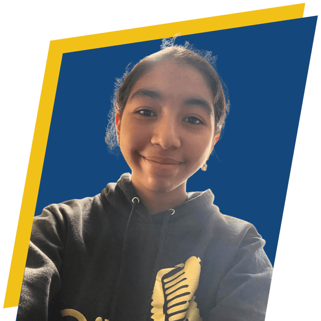 A peer mentor with dark hair, wearing a black hoodie, smiles at the camera against a blue background with a yellow frame