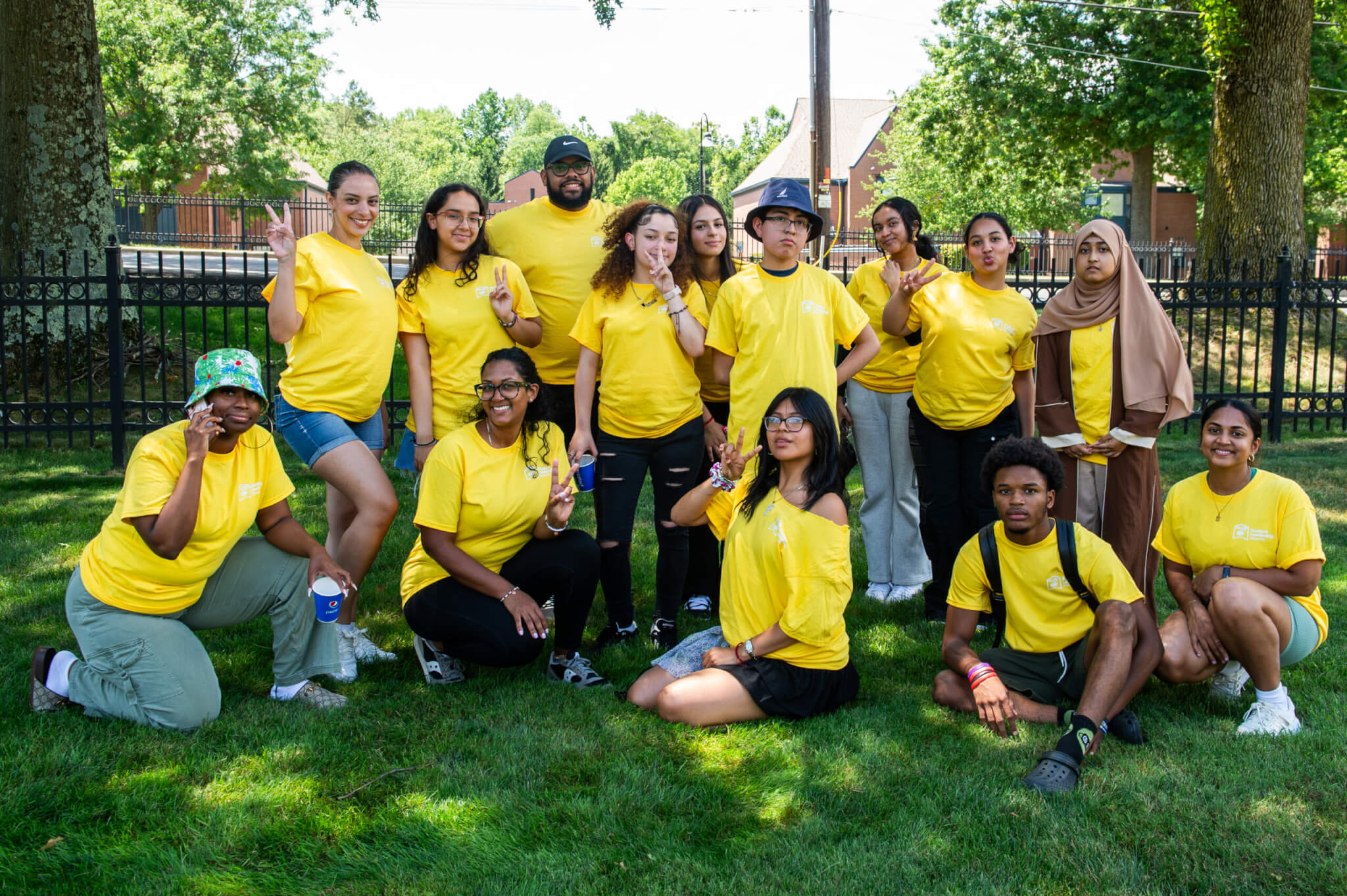 Students in matching yellow shirts gather in front of a college campus for a college preparation program designed for first-gen students and other high school groups