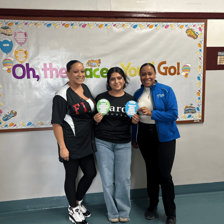 Three women stand indoors in front of a wall display reading Oh, the Places You’ll Go! Two of them hold colorful paper cutouts, showcasing a Fordham Leadership Academy program highlight that celebrates college dreams.
