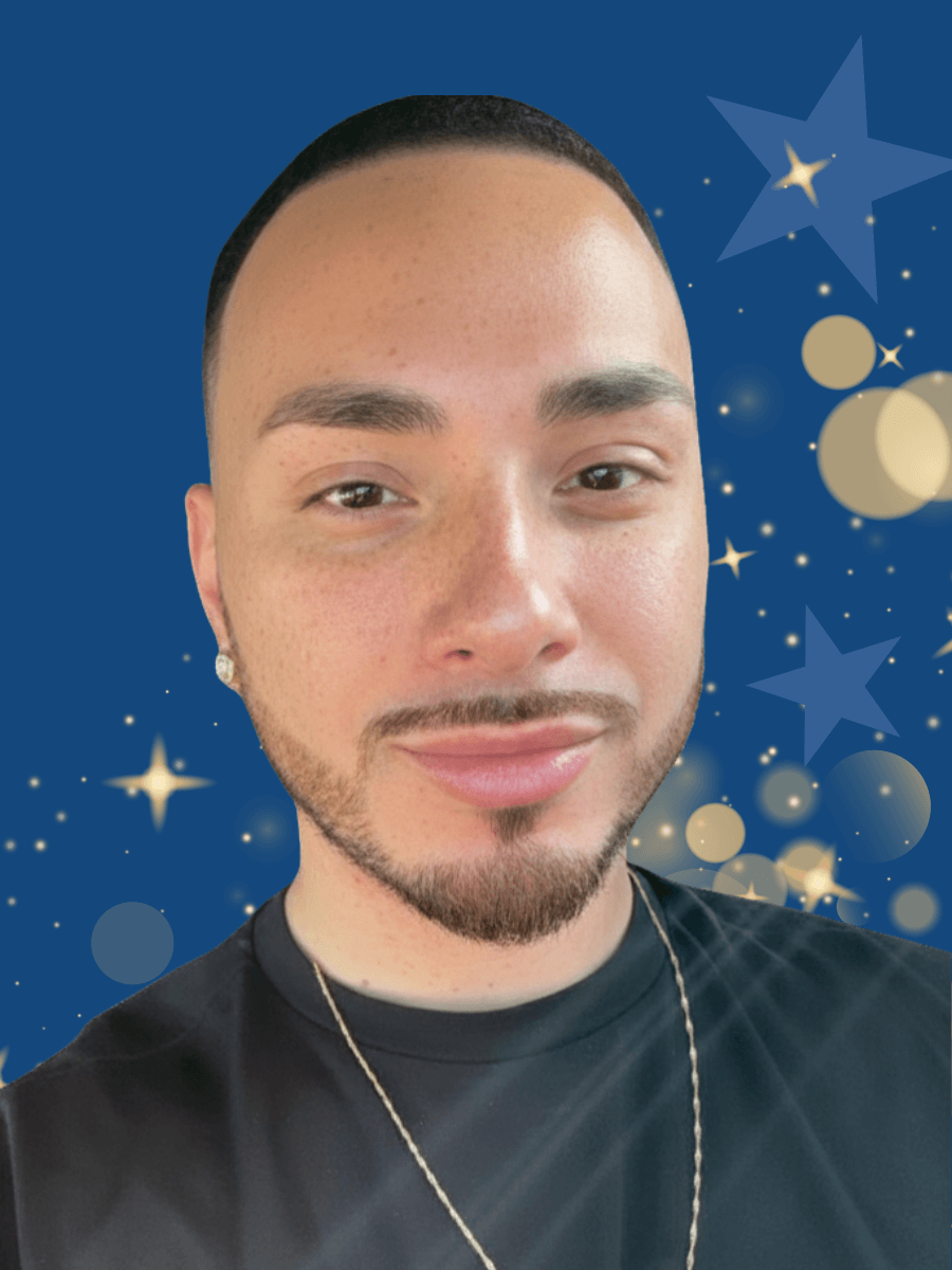 A person with neatly groomed facial hair and short hair smiles slightly, wearing a black shirt and gold chain, with a blue background featuring stars and circular light effects