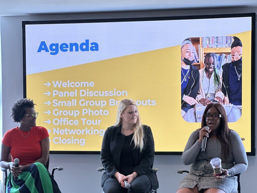 Three women sit on a panel in front of a projected agenda slide listing welcome, panel discussion, small group breakouts, group photo, office tour, networking at Sony