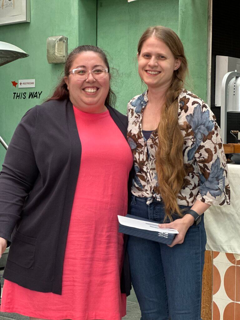 Two women stand side by side indoors at the network's April Blount Awards