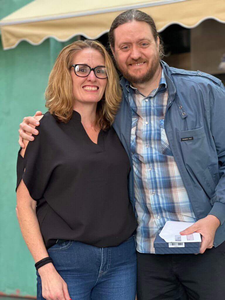 Two people stand close together outdoors, smiling at the camera for the network's April Blount Awards