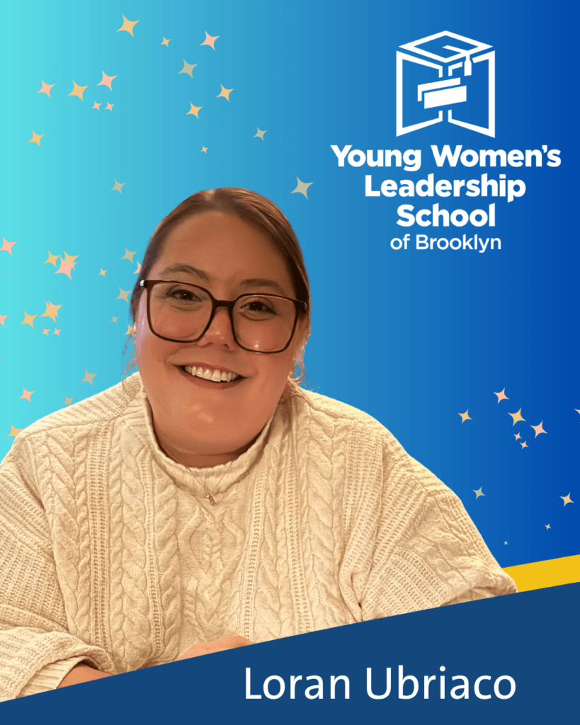 A woman in glasses and a white sweater smiles in front of a blue background with the Young Women’s Leadership School of Brooklyn logo and the name Loran Ubriaco for the network's April Blount Awards