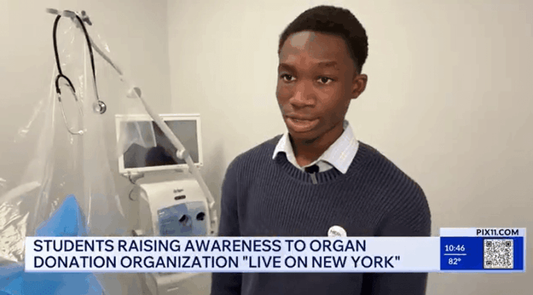 A student stands in a medical room, speaking; text on screen reads Students raising awareness to organ donation organization Live On New York.