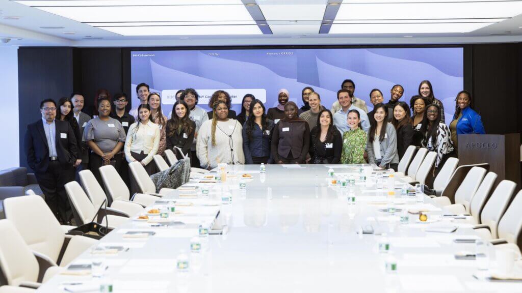 A group of people pose for a photo at the end of a long conference table in a modern meeting room at the Apollo Opportunity Foundation.