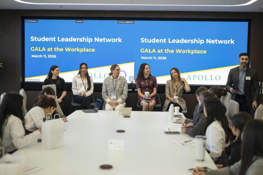 A panel of six speakers sits in front of a screen displaying Student Leadership Network GALA at the Workplace, March 11, 2026, while an audience listens and takes notes during the Apollo Opportunity Foundation event.