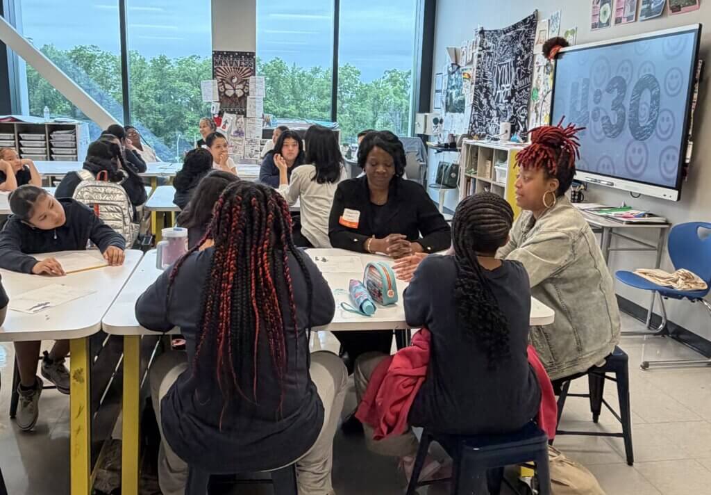 Students and adults sit around tables engaged in group discussions on early career exploration for Cool Careers Potential Paths