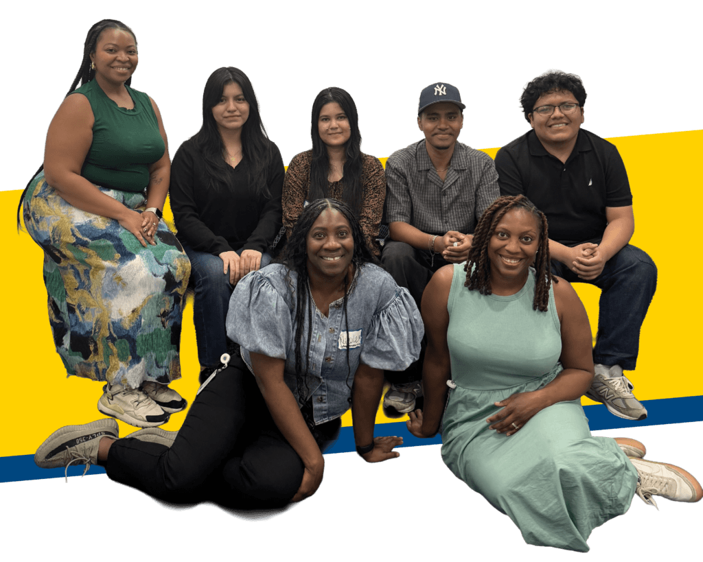 Seven people pose together for the 2025 Annual Report in front of a white background with a yellow and blue design; five are seated on a bench, and two are sitting on the floor in front.