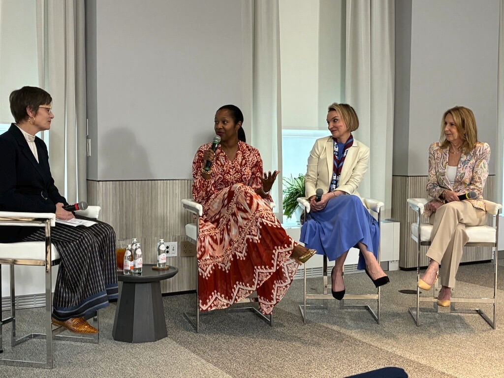 Four women sit on stage in conversation, with microphones, at The Estée Lauder Companies' Good Works Purpose Week panel
