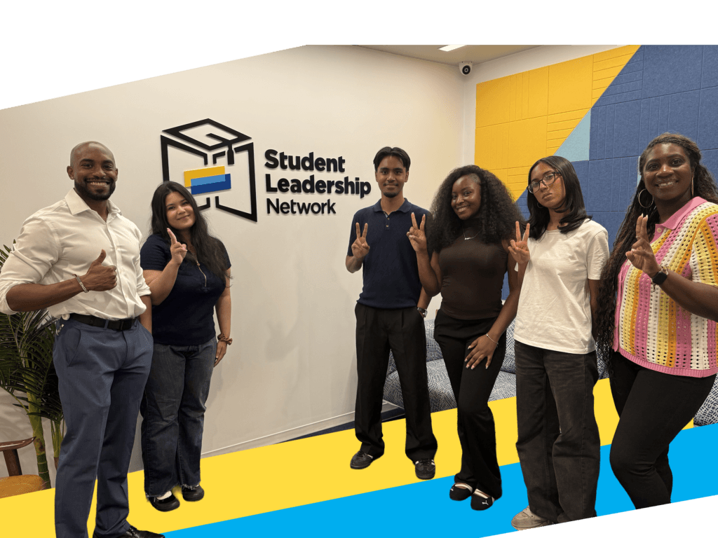 CollegeJourney Peer Leaders and staff stand in front of a Student Leadership Network sign, smiling and making peace signs