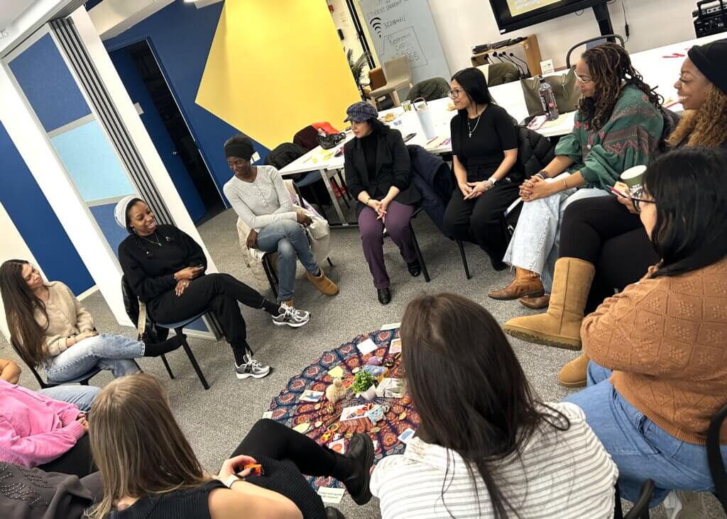 A group of school counselors and social workers sit in a circle, engaged in discussion, at a Girls'+ Education convening supported in part by the Estee Lauder Companies