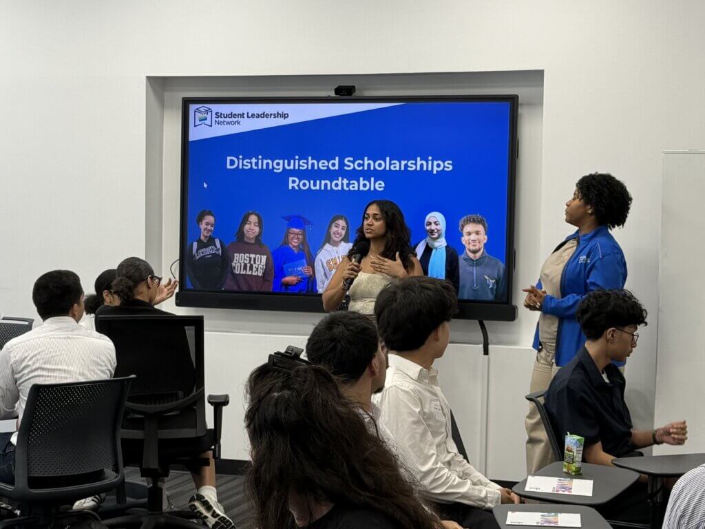 Two counselors speak to a group of students in a classroom about QuestBridge and Posse scholarships