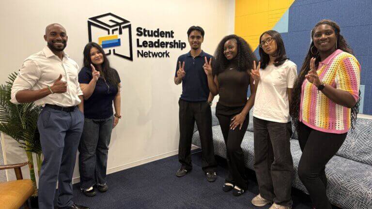 CollegeJourney Peer leaders and staff stand in front of a Student Leadership Network sign
