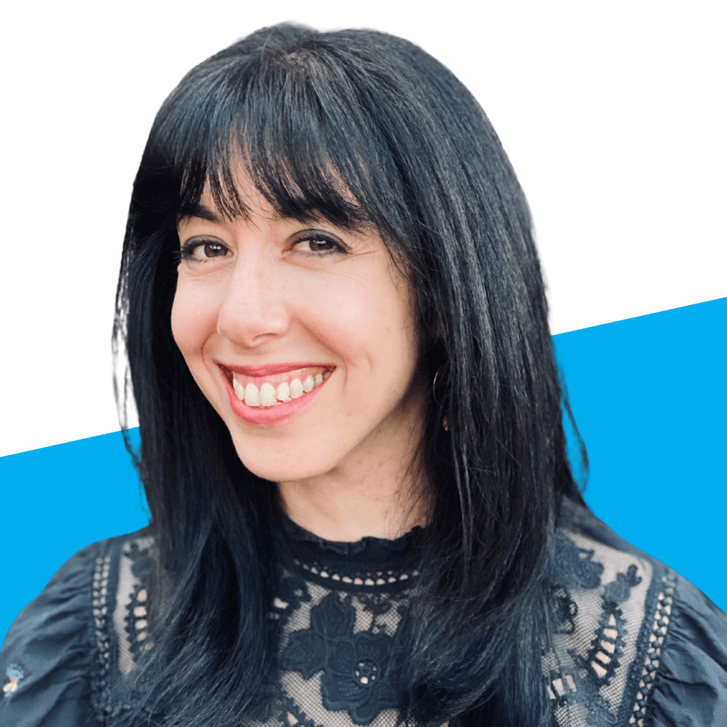 Woman with long black hair and bangs smiling, wearing a black lace top, in front of a white and blue background—one of the passionate Voices Behind the Mission.